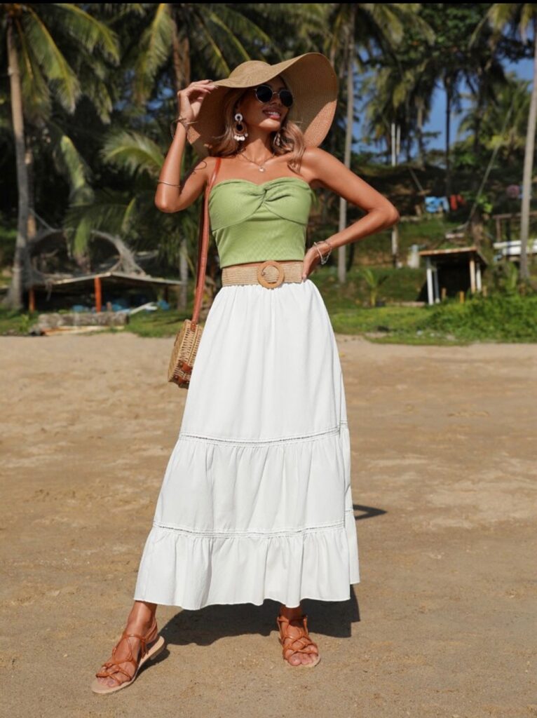 Girl wearing a white maxi skirt, green crop top and sun hat.